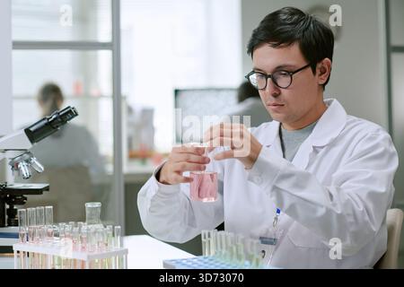 Jeune homme adulte conduisant une expérience chimique dans un laboratoire médical Banque D'Images