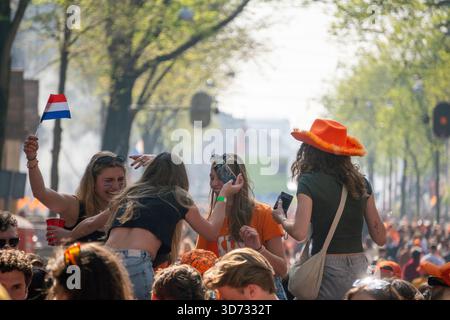 Amsterdam, pays-Bas - 26.04.2025 : les gens portés en orange flottant dans des bateaux près des canaux d'Amsterdam le jour du Roi. Banque D'Images