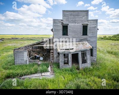 Vieille maison délabrée se trouve dans un champ d'herbe. La maison est dans un état de délabrement, avec des fenêtres cassées et un toit qui manque. L'environnement Banque D'Images