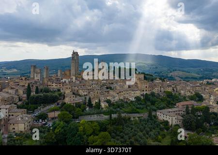 Vue aérienne des tours médiévales et des remparts en pierre de San Gimignano en Toscane, une ville de colline du XIIIe siècle classée au patrimoine mondial de l'UNESCO sous des nuages spectaculaires. Banque D'Images