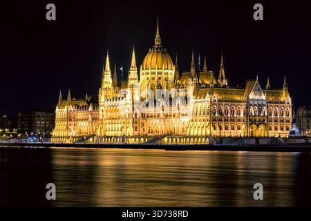 Panorama nocturne du bâtiment illuminé du Parlement hongrois à Budapest, avec un éclairage architectural doré reflétant le Danube et Banque D'Images
