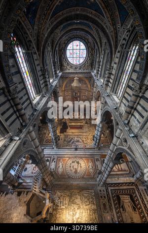 Sienne, Italie - 19 juillet 2025 : les majestueuses arches gothiques de l'intérieur de la cathédrale de Sienne, renommées pour ses rayures de marbre noir et blanc, sa fresque vibrante Banque D'Images