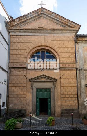 Façade en pierre de l'église des Saints Antoine Abbé et Catherine à Acquapendente, Italie. Architecture romane, porte en bois vert, vent voûté Banque D'Images