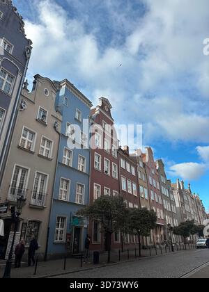 Maisons historiques colorées bordant une rue pavée sous un ciel bleu partiellement nuageux Banque D'Images