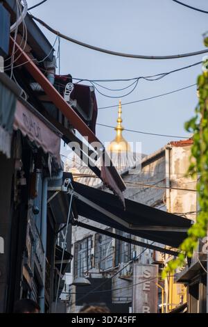 Dôme de mosquée doré visible à travers la vieille rue du quartier d'Istanbul avec des câbles et des bâtiments - paysage urbain montrant l'architecture ottomane historique Banque D'Images