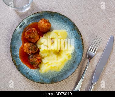assiette ronde blanche avec boulettes de viande saupoudrées d'aneth haché dans une sauce tomate avec purée de pommes de terre Banque D'Images
