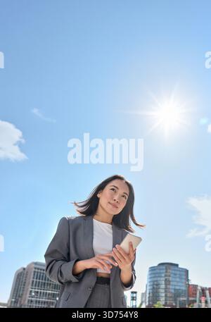 Jeune femme d'affaires asiatique porte costume debout dans la rue de la ville à l'aide du téléphone Banque D'Images