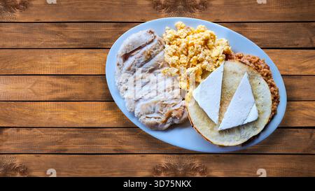 Petit déjeuner traditionnel avec calentado (riz et haricots), arepa avec fromage frais, œufs brouillés et porc. Banque D'Images