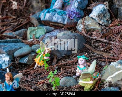 De minuscules figurines de fées nichées parmi les rochers et les aiguilles de séquoia dans un jardin miniature fantaisiste. Banque D'Images