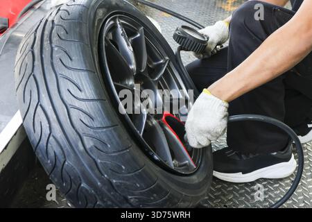 Gonflage d'un pneu de voiture avec compresseur d'air par auto-mécanicien focalisé. Ce service professionnel implique la vérification de la pression des pneus pour la sécurité du véhicule et les principaux Banque D'Images