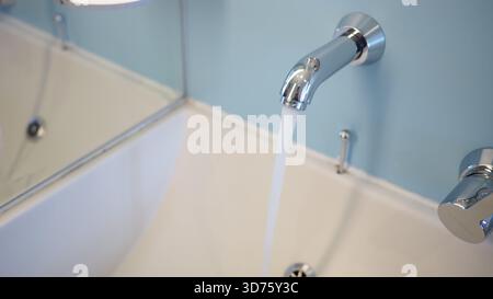 Robinet de salle de bains moderne avec de l'eau courante dans un espace propre Banque D'Images