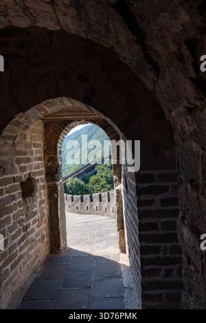 Une tour de guet restaurée de la Grande Muraille se trouve bien en vue sur une crête boisée. L'escalier en pierre escarpé et le mur incurvé mettent en valeur le HIS Banque D'Images