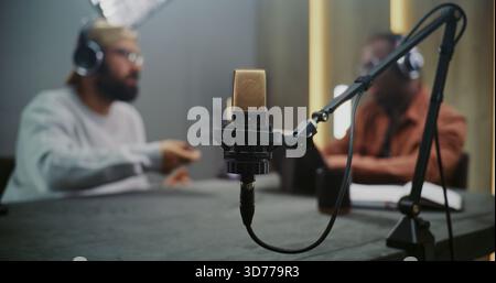 Gros plan sur la configuration du microphone de studio haute qualité pour la session d'enregistrement. Deux professionnels masculins hors de propos. Concept de préparation méticuleuse derrière la radiodiffusion professionnelle et la création de contenu. Banque D'Images