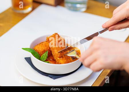 femme profitant d'un plat de croquettes dorées tout en étant assise à une table dans un café Banque D'Images