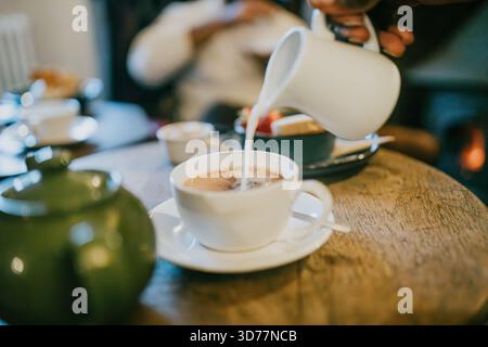 Une tasse blanche de café est versée dans une tasse. La tasse est sur une table en bois Banque D'Images