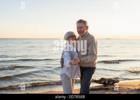 Continuez à bouger. Romantique couple senior mature dansant ensemble sur les loisirs de plein air de la plage. Heureuse famille souriante homme retraité femme mari femme s'amusant profiter du temps ensemble. Family moment Love Care || autorisation du modèle Banque D'Images