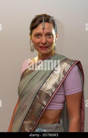 Une femme pose dans un sari indien avec des bijoux, debout dans un cadre de studio neutre Banque D'Images