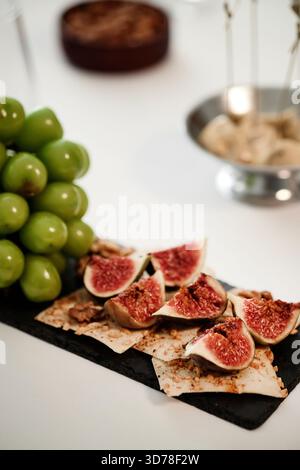 Gros plan sur des figues et des raisins frais servis sur des craquelins lors de la dégustation de vins Banque D'Images