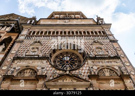 Une perspective vers le haut capture la façade ornée de la Capella Colleoni, une chapelle Renaissance à Bergame, en Italie, sous un ciel partiellement nuageux. Banque D'Images
