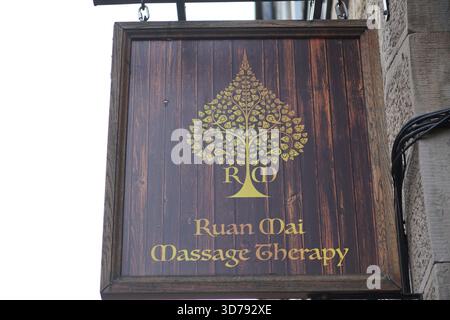 Enseigne en bois pour Ruan mai massage Therapy avec un logo d'arbre d'or sur un mur extérieur.Edinburgh, Écosse Banque D'Images