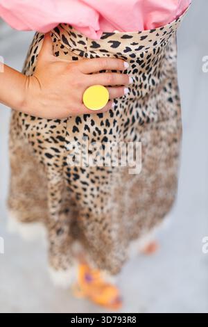 jeune femme portant un haut rose et une jupe à imprimé léopard avec un anneau de disque jaune lors d'un événement extérieur décontracté Banque D'Images