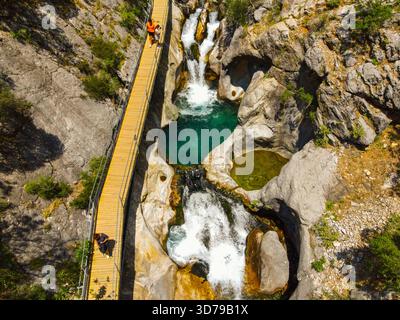 Alanya, Turquie - 13 juin 2024 : vue aérienne d'un homme et d'une femme marchant sur une promenade en bois le long d'une série de petites cascades et po turquoise Banque D'Images