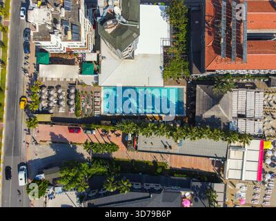 Alanya, Turquie - 13 juin 2024 : vue aérienne de haut en bas de la piscine rectangulaire d'un hôtel, d'une route côtière adjacente avec circulation et de l'entrée du bus Banque D'Images