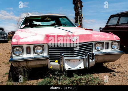 Cette ancienne Cadillac Sedan DeVille abandonnée, peinte en rose clair, repose dans une casse désertique le long de l'historique route 66 des États-Unis en Arizona. Banque D'Images