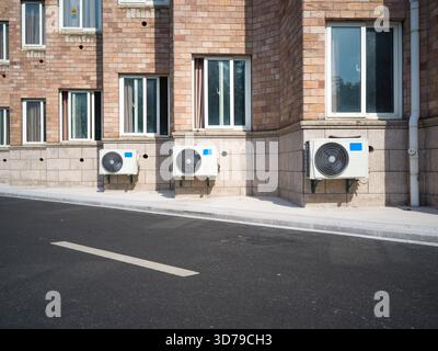 Unité AC attachée à un bâtiment en briques avec fenêtres à cadre blanc Banque D'Images