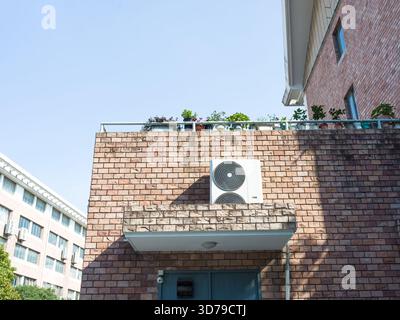 Unité AC attachée à un bâtiment en briques avec fenêtres à cadre blanc Banque D'Images