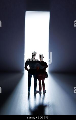 Jeune couple debout devant la porte ouverte avec des lumières qui passent à travers Banque D'Images