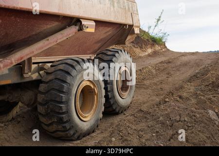 La machinerie lourde travaille sur un chemin de terre sur un chantier de construction pendant un après-midi nuageux Banque D'Images