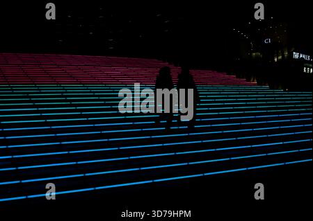 Silhouettes descendant les marches éclairées au néon devant un hôtel de Pékin la nuit Banque D'Images