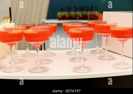 Boissons alcoolisées rouges avec des agrumes sur une table de buffet pendant les vacances.Un groupe de verres remplis de punch rouge sont affichés sur une table de banquet Banque D'Images