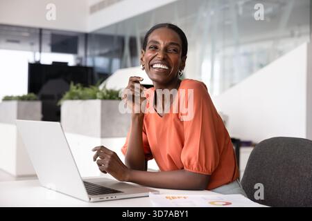 Joyeuse jeune femme analyste d'affaires afro-américaine regardant loin Banque D'Images