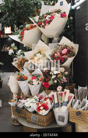 Bouquets de fleurs fraîches exposés dans une boutique de fleuriste, disposés dans du papier d'emballage blanc Banque D'Images