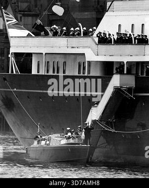 Queen monte à bord de Royal Barge in the Pool - la Queen descend la passerelle du yacht royal Britannia - dérangé à Battle Bridge Tier dans le Pool de Londres - à la Royal Barge aujourd'hui (samedi) pour le court voyage à Westminster Pier où, avec le duc d'Édimbourg, elle devait mettre le pied sur le fort en sol anglais la première fois depuis qu'ils sont partis pour leur tournée du Commonwealth il y a près de six mois. On voit juste à bord de la barge royale la reine Elizabeth la reine mère qui, avec la princesse Margaret, était allée à l'étranger sur le yacht royal pour accueillir la reine et le duc à leur arrivée dans la piscine aujourd'hui. Ma Banque D'Images