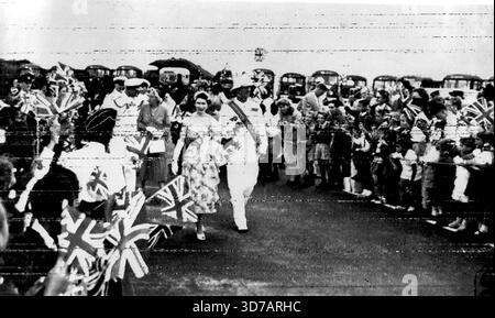 Les écoliers encouragent la reine -- les écoliers agitant "Union Jacks" saluent la reine alors qu'elle marche de Kindley Field avec le gouverneur Sir Alexander Hood après son arrivée aux Bermudes par avion aujourd'hui, 24 novembre. Après la reine, le duc d'Édimbourg et Lady Hood parlent étroitement. 24 novembre 1953. (Photo d'Associated Press photo). Banque D'Images