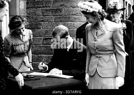 Journée royale aux frontières -- la famille royale, accompagnée du lieutenant Mountbatten, a reçu un accueil formidable, et la princesse Elizabeth et sa fiancée ont été très acclamées. Les amoureux royaux de Galashiels. La princesse Elizabeth regarde avec un sourire tandis que le lieutenant Philip Mountnatten signe le livre des visiteurs à l'extérieur de l'hôtel de ville. Signez ici, bonne photo des amoureux royaux signant le livre des visiteurs à l'hôtel de ville de Galashiels. 22 juillet 1947. Banque D'Images