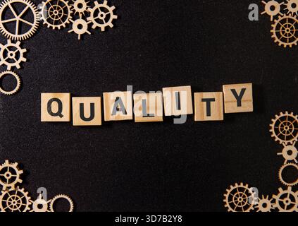 Le mot QUALITY fait de cubes en bois sur fond bleu. Photo conceptuelle Banque D'Images