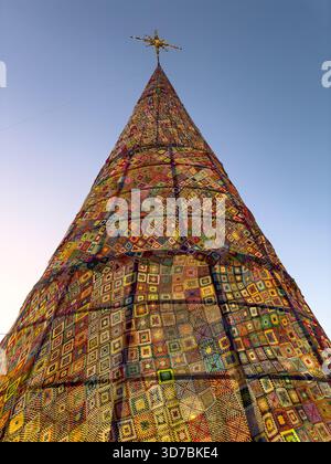 Une prise de vue extrêmement basse souligne la hauteur colossale et la forme conique de l'arbre de Noël à Ovar, au Portugal, qui est recouvert d'un vibran complexe Banque D'Images