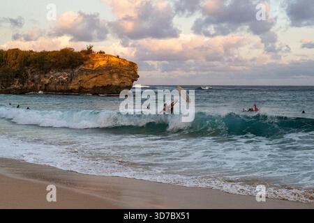 Un surfeur vole dans les airs à Shipwreck Beach près de Makawehi point à la fin de la journée. Banque D'Images