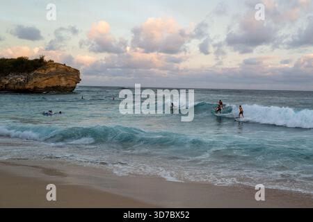 Surfeurs et bodyboarders en fin de journée à Shipwreck Beach près de Makawehi point. Banque D'Images