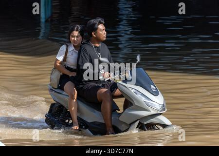 BANGKOK, THAÏLANDE, nov 09 2025, Une paire conduit une moto dans une rue inondée Banque D'Images