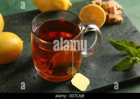 Tasse de thé chaud avec des citrons et des feuilles de menthe sur fond grunge vert Banque D'Images
