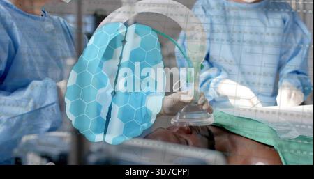 Maintien de l'anesthésiste fixant un masque à oxygène transparent au-dessus du patient sur la TABLE DU BLOC OPÉRATOIRE, blouse bleue, recouvrement cérébral Banque D'Images