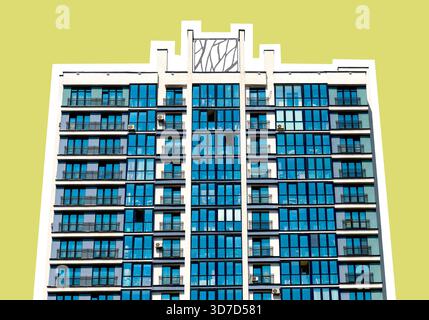 Vue frontale d'un immeuble résidentiel moderne de grande hauteur avec fenêtres en verre bleu symétriques et balcons. La structure est isolée contre un YE plat Banque D'Images