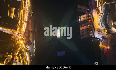 Vue aérienne des lumières rayonnantes reflétant les eaux tranquilles à côté des bateaux amarrés, un contraste vibrant avec la nuit sombre, Xiangxi Tujia et Miao Auton Banque D'Images