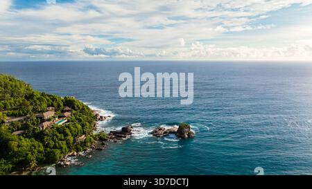 Une forêt verte dense couvrant un littoral rocheux, aux eaux turquoises claires. Seychelles, Mahé. Banque D'Images