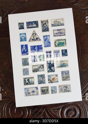 Une feuille de timbres-poste bleus vintage du monde entier sur une table en chêne sculpté. Banque D'Images